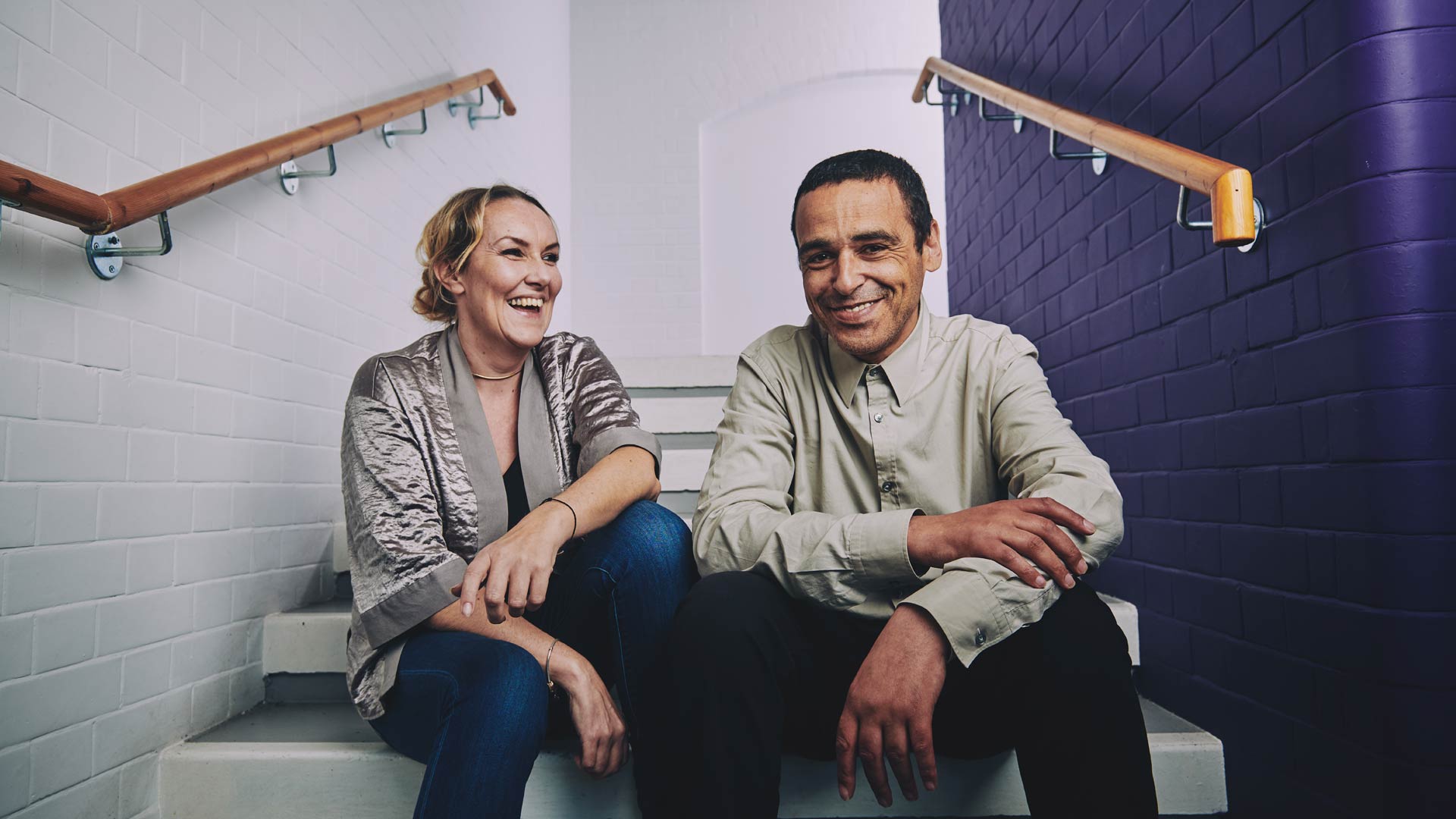 a woman and a man sitting on the stairs laughing