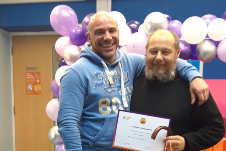 Someone receiving a certificate at our Reading service. There is a balloon arch behind them!